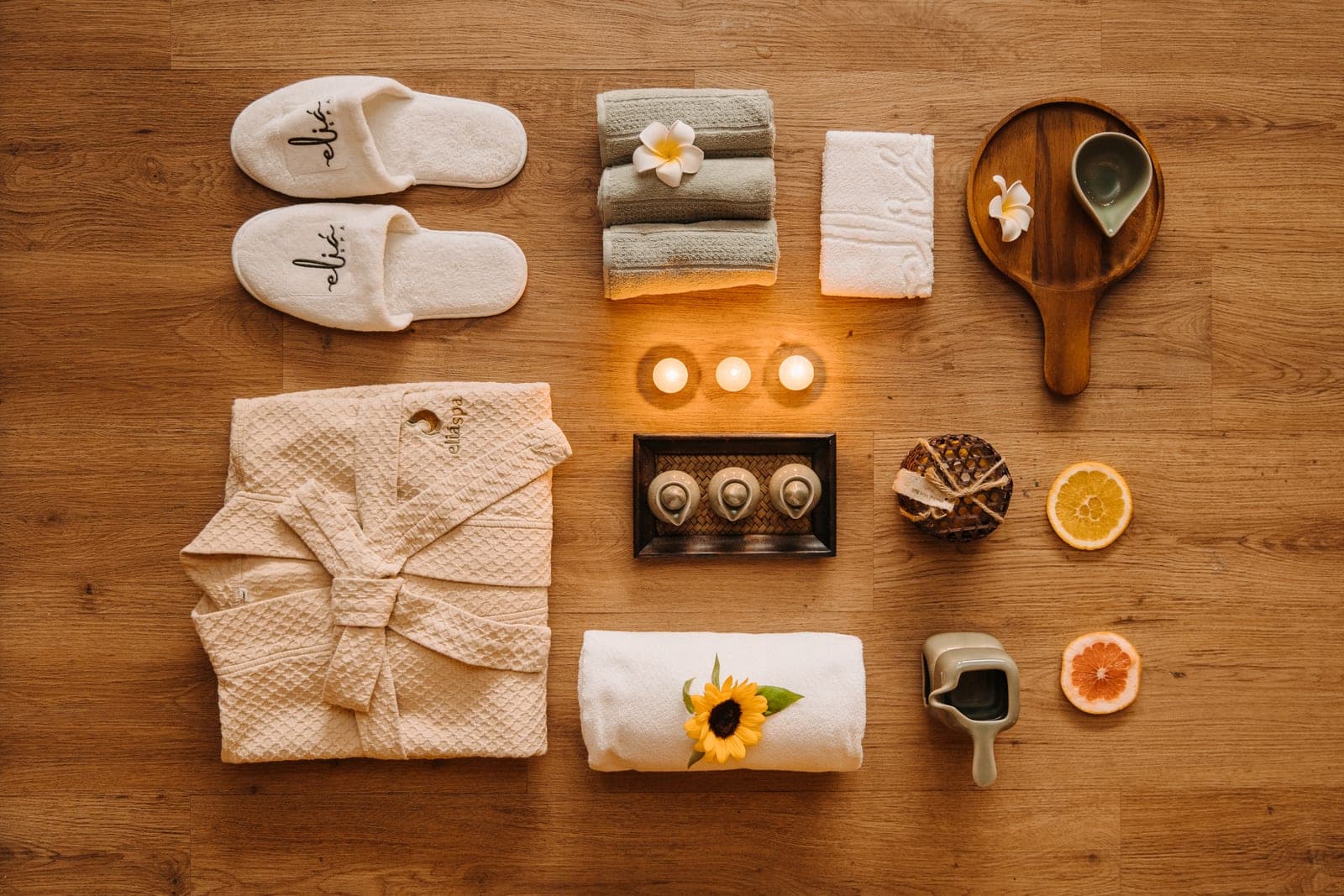 Pantufas, roupão, toalhas, velas e amenidades da Eliá reunidos em composição sensorial
