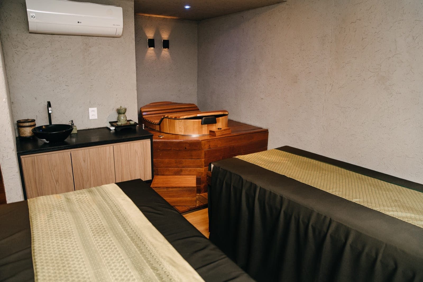 Sala de atendimento com maca e ofurô de madeira